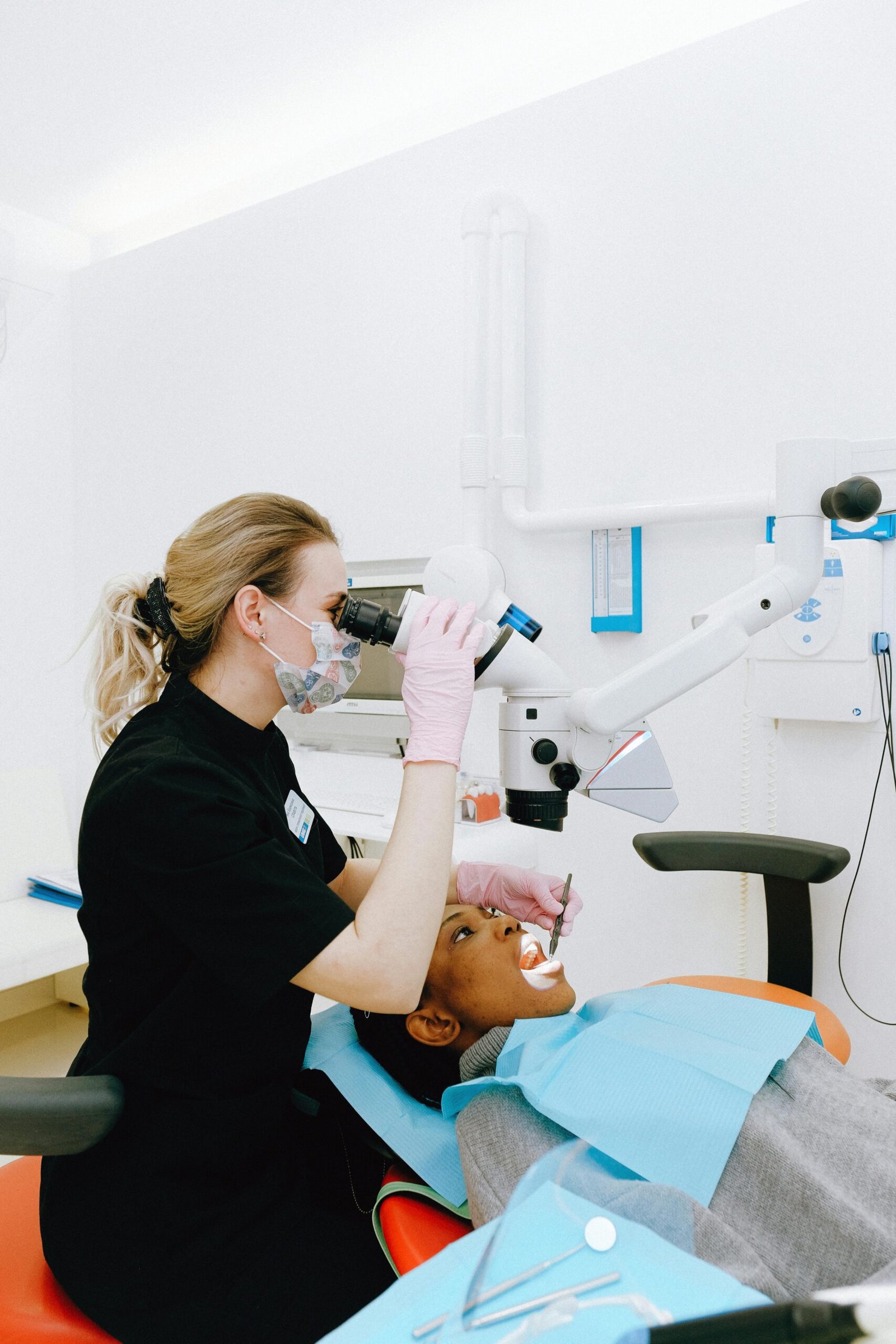 A dentist using advanced equipment during a dental exam in a clinic.